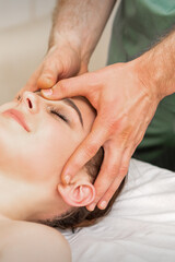 Fototapeta na wymiar Pretty young caucasian woman receiving a head massage by a male massage therapist in a beauty salon