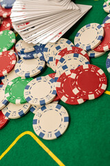 a deck of cards laid out in a fan with colored chips on a green professional poker table.