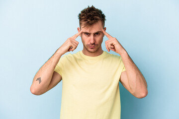 Young caucasian man isolated on blue background focused on a task, keeping forefingers pointing head.