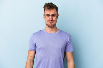 Obraz premium Young caucasian man isolated on blue background blows cheeks, has tired expression. Facial expression concept.