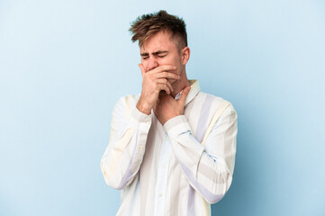 Young caucasian man isolated on blue background suffers pain in throat due a virus or infection.