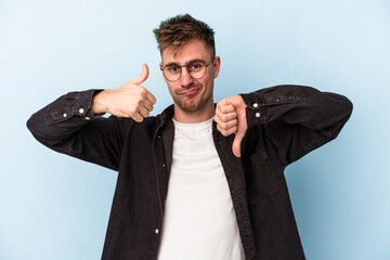 Young caucasian man isolated on blue background showing thumbs up and thumbs down, difficult choose...