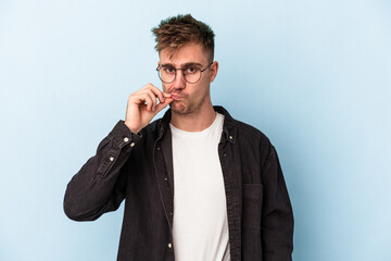Young caucasian man isolated on blue background with fingers on lips keeping a secret.