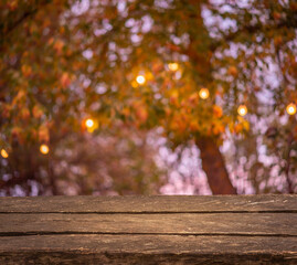 Naklejka na ściany i meble Empty old vintage wooden table. Bokeh colorful sunset and forest trees. String of lights. Template mock up for display of product