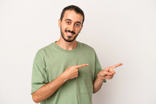 Young caucasian man isolated on white background excited pointing with forefingers away.