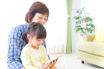 Naklejka premium おばあちゃんとスマホを使う子供