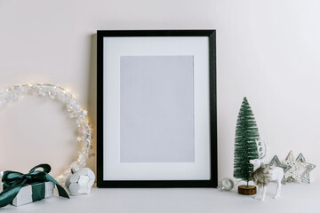 Mock up frame with Christmas decorations. Christmas composition with fir tree branch, deer, candle and silver stars on white background.