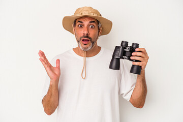 Middle age caucasian man holding binoculars isolated on white background  surprised and shocked.