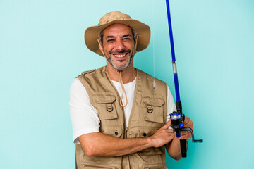 Middle age caucasian fisherman holding rod isolated on blue background  laughing and having fun.