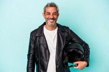 Middle age biker caucasian man holding helmet isolated on blue background  happy, smiling and cheerful.