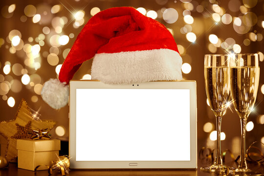 Christmas mockup. Blank tablet and Santa hat on blurred background of winter holiday.