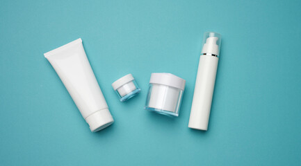 jar, bottle and empty white plastic tubes for cosmetics on a blue background. Packaging for cream, gel, serum, advertising and product promotion