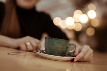 A cup of tea or coffee close-up. Woman’s hands and cup. Woman drinking tea or coffee in a cafe.