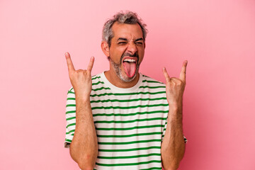 Middle age caucasian man isolated on pink background  showing a horns gesture as a revolution concept.