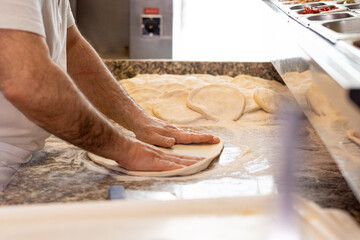 Mani che impastano la pizza