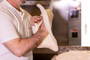 Pizzaiolo fa roteare impasto per la pizza