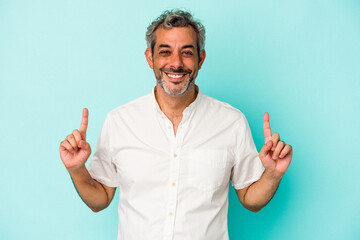 Middle age caucasian man isolated on blue background  indicates with both fore fingers up showing a...