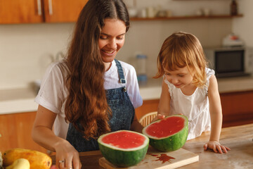 Beautiful Caucasian Mother and Daughter eating Watermelon at Home Kitchen