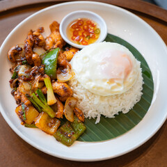 Thai food, Stir-fried chicken with cashew nuts top on rice on a wooden table. Consists of chicken, Thai Cashewnuts, sweet pepper, spring onion, with gravy oyster sauce juicy.