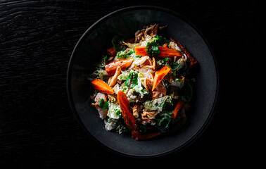 Chicken, carrot, lettice and tomato salad on black plate