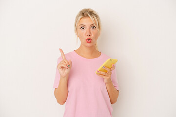 Young Russian woman holding mobile phone isolated on white background having some great idea, concept of creativity.