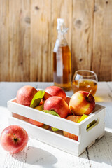 Apples in wooden box, juice in the glass and bottle on the wooden background