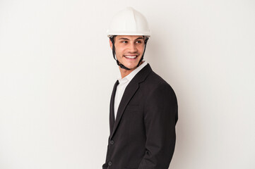 Young architect caucasian man isolated on white background looks aside smiling, cheerful and pleasant.