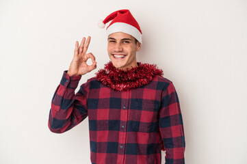 Young caucasian man celebrating Christmas isolated on white background cheerful and confident showing ok gesture.