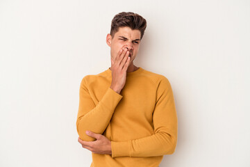 Young caucasian man isolated on white background yawning showing a tired gesture covering mouth with hand.