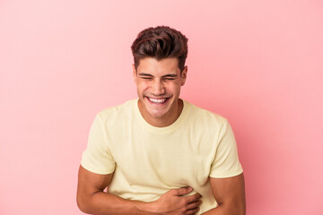 Young caucasian man isolated on pink background laughing and having fun.