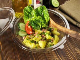 Potato Salad with Bacon in a Plastic Bowl on wooden Background