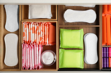 Storage of different feminine hygiene products in wooden drawer, top view