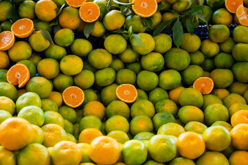 Many green tangerines on the counter in the market.