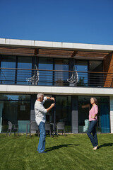 Obraz premium Elderly man photographing woman in house yard