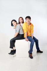 Fototapeta premium Group of young south east asian mixed race man woman chinese malay sit on box pose white background moody relax fashion students colleagues look at camera