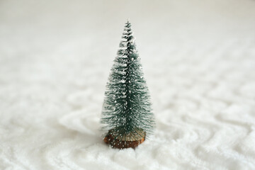 Toy Christmas tree on a wooden stand on a white background