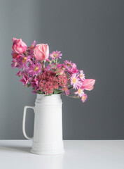 pink flowers in white jug on background gray wall