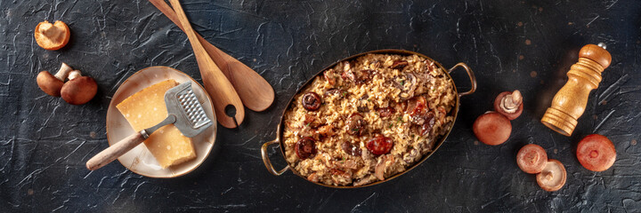 Risotto ai funghi, mushroom rice panorama, with ingredients, overhead flat lay shot on a black background