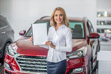 Woman showing document in car showroom
