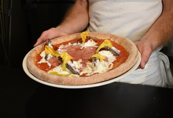 Pizzaiolo con pizza ai gamberi