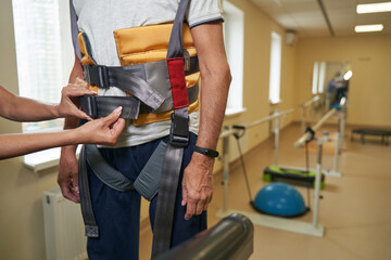 Stroke man uses harness system in rehabilitation center