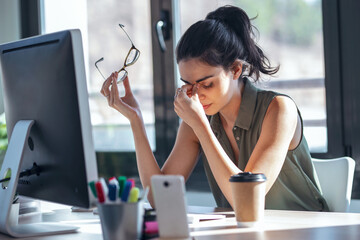 Tired business woman with headache looking uncomfortable while working with computer in the office
