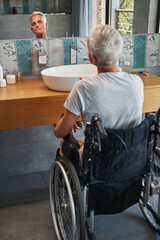 Pensioner with disability checking his face in mirror