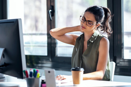 Tired Business Woman With Neck Pain Looking Uncomfortable While Working With Computer In The Office.