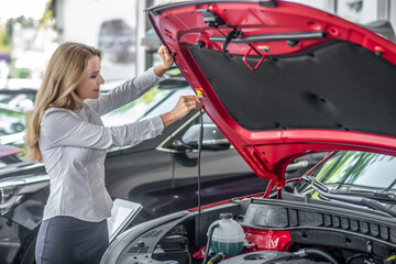 Smiling confident woman opening car hood