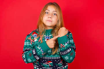 Obraz na płótnie Canvas brunette kid girl in knitted sweater christmas over red background in hurry pointing to watch time, impatience, upset and angry for deadline delay