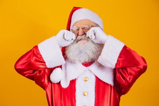 Santa Claus crying with his hands in his eyes.