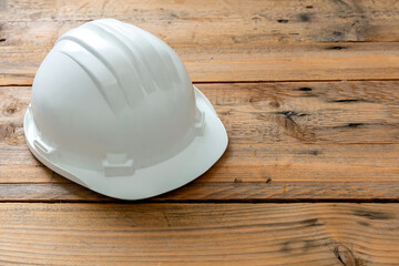 Safety helmet, white color hard hat, construction site engineer protective gear wooden background