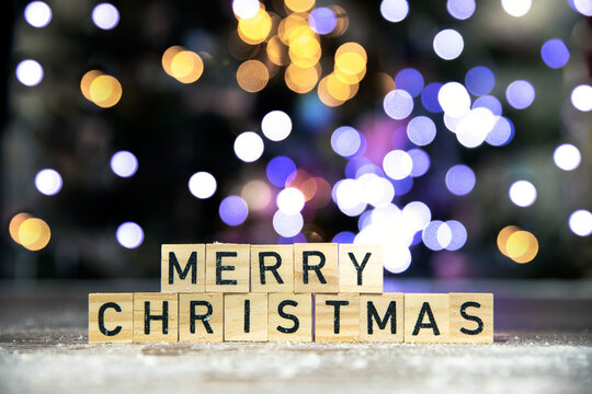 Merry Christmas text written with bokeh cbackground of Christmas tree in the snow, copy space, Holiday, Santa and xmas concept