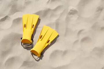 Pair of yellow flippers on sand, top view. Space for text © New Africa